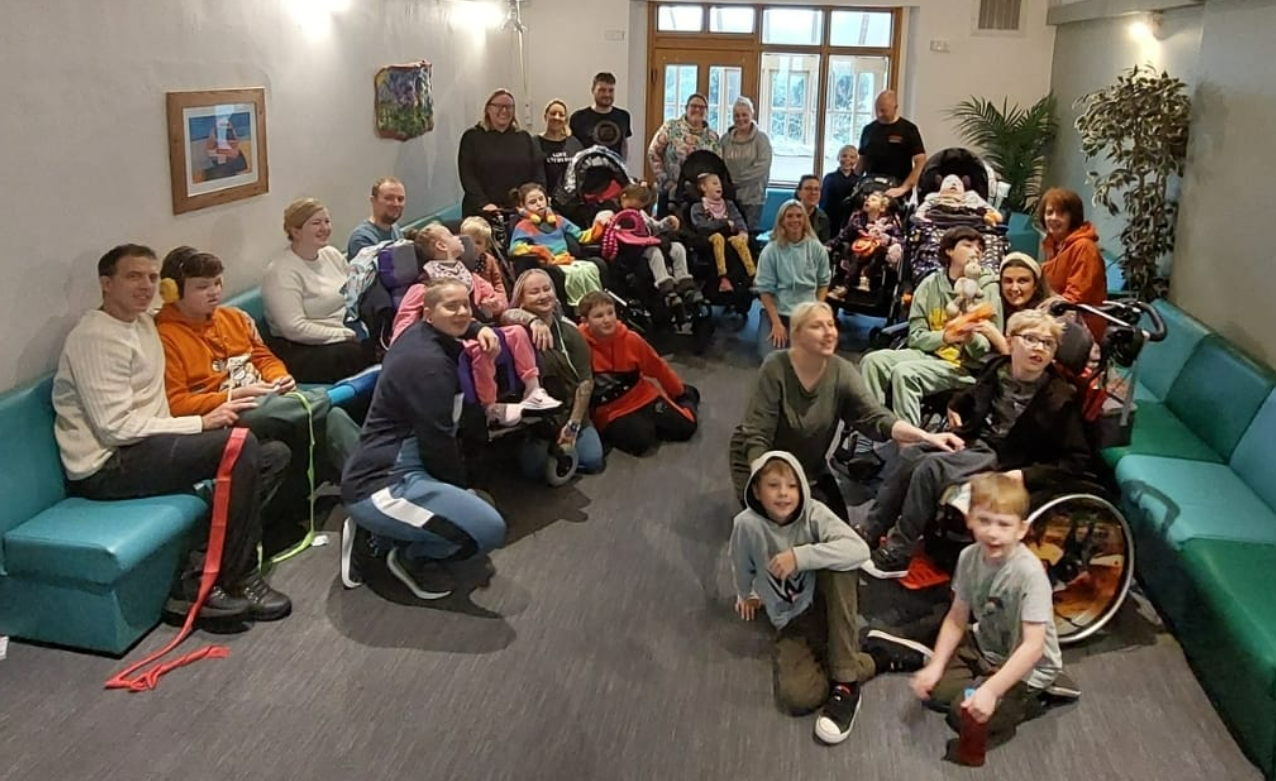 A group photo of adults and children smiling as they sit on sofas at an activity weekend