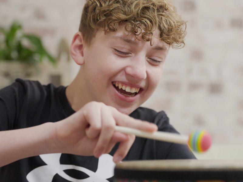 Charlie smiling while playing with his drum kit
