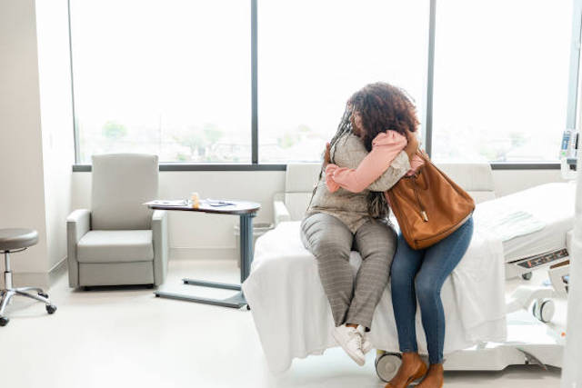 Two women hugging in a hospital room following maternity services in Wales