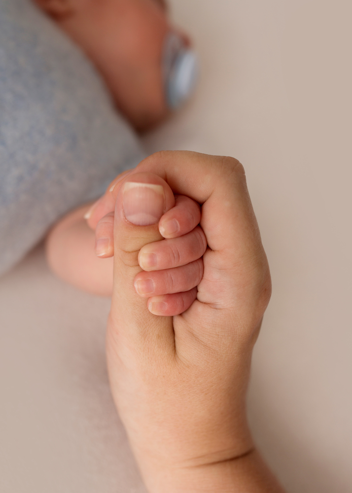 adult hand holds baby's hand while concerned about hie grades