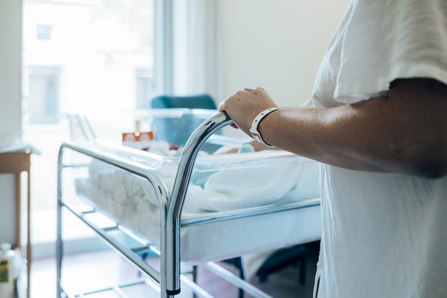 mum's hand holding cot while worrying about the long term effects of lack of oxygen at birth