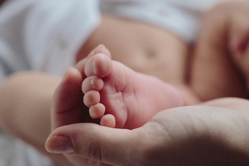 adult hand holding baby's feet