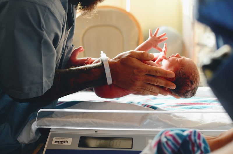 image of baby being held above electronic scales
