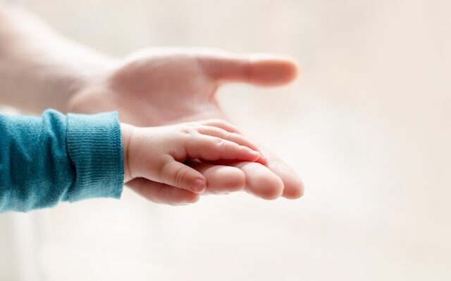 a parent father holds the hand of a small child who has been diagnosed with (hie) hypoxic Ischaemic encephalopathy