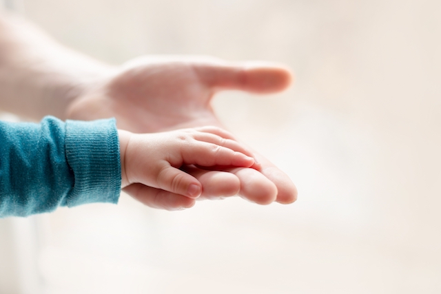 a parent father holds the hand of a small child who has been diagnosed with (hie) hypoxic Ischaemic encephalopathy